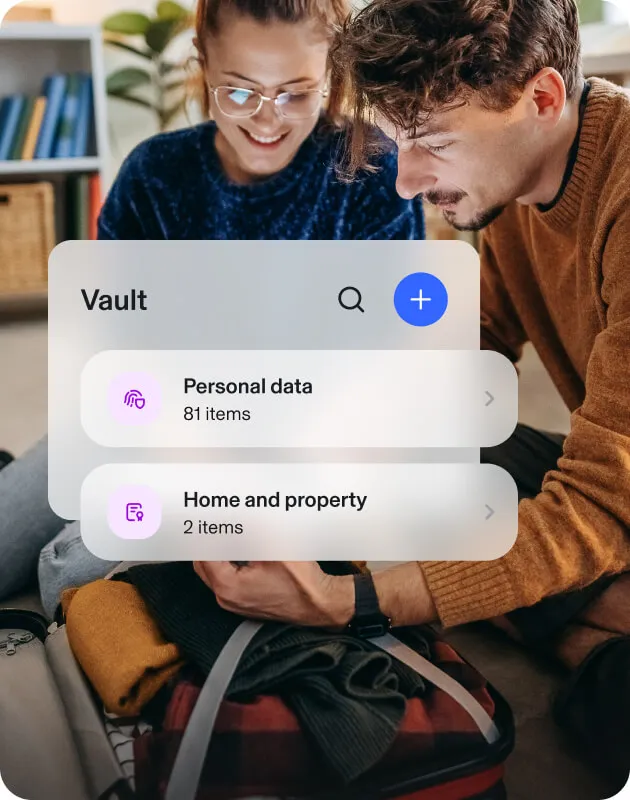 Smiling couple seated on the floor, using a tablet, beside an Aura Vault popup that confirms their personal data is encrypted